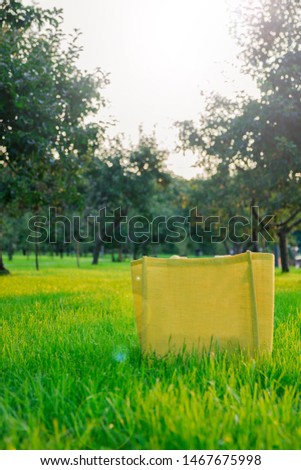 empty yellow jute shopping bag on green grass in Apple orchard in nature.