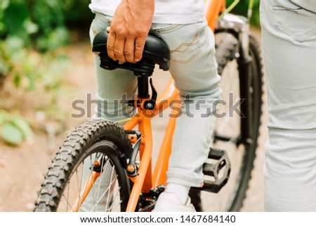 cropped view  of father holding sit of bicycle to help son to ride