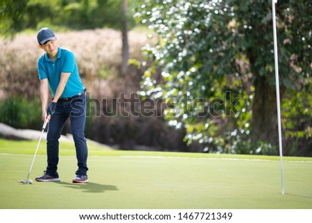 The male golfer is aiming a golf ball on the pitch.