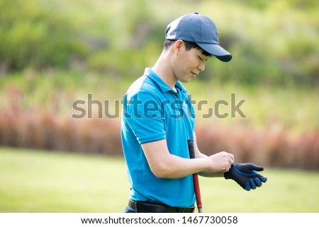 Male golfer is wearing gloves before start golfing.