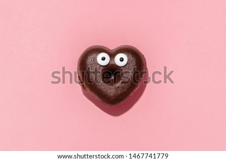 Funny heart shaped choco donut on a pastel pink background, creative minimal Valentine concept