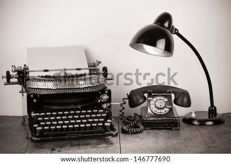 Vintage typewriter, old telephone, retro lamp on table