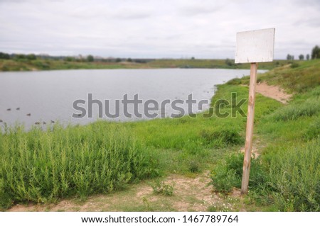 Empty sign board near pond. Space for text.