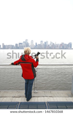 Rear view of woman tourist looking out over the river towards Manhattan.