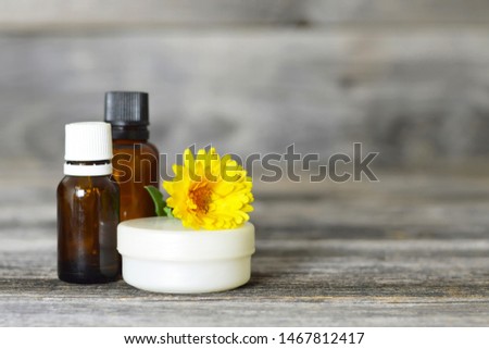 Calendula oil, cream and flower on wooden background