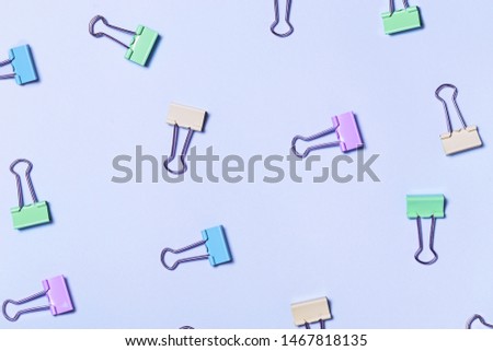 Different bright paper clip pattern on pink background. Top view, flat lay. Minimal school or office stationery.