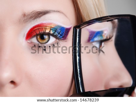 Face of young girl with a mirror in a hand, its eye is reflected in which