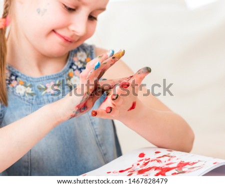 Cute female child is using her hands as palette, close-up