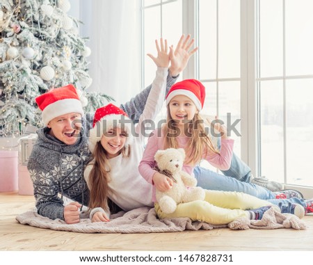 Smiling family in santa hats lying together near christmas tree