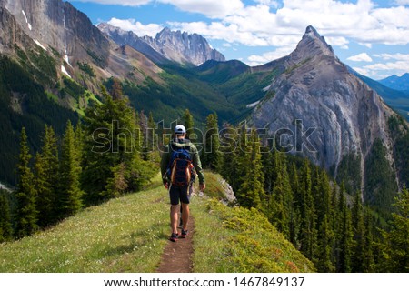 Healthy young man and a woman hiking  and enjoying the view from the top of King Creek Ridge, Kananaskis Country, Alberta, Canada on a bright sunny day. Back packing in the Canadian Rockies. Royalty-Free Stock Photo #1467849137