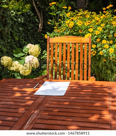 Wooden table with a sheet of paper in summer