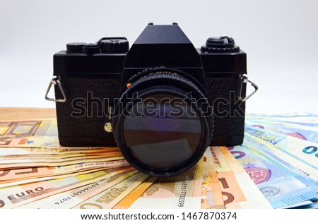 Camera and money on wooden table. Concept for microstock photography