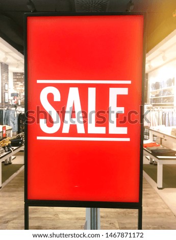 Vertical illuminated SALE sign light box in front of clothes store