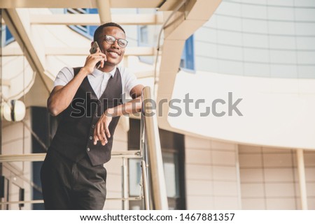 Young african american business man in suit and eyeglasses talking on the phone on the background of the business center