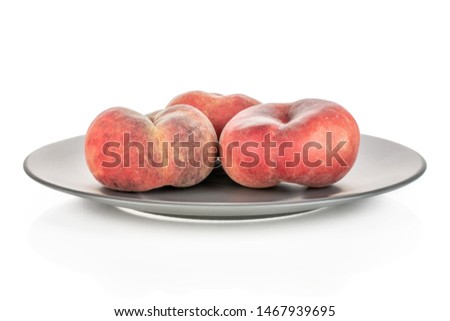 Group of three whole fresh red peach prunus persica platycarpa on gray ceramic plate isolated on white background