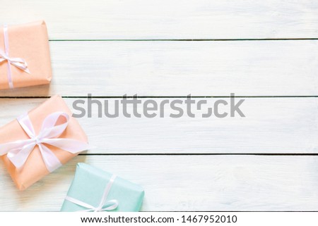 Presents in multicolored craft paper decorated with striped ribbon bows on white rustic table. Holidays concept. Top view