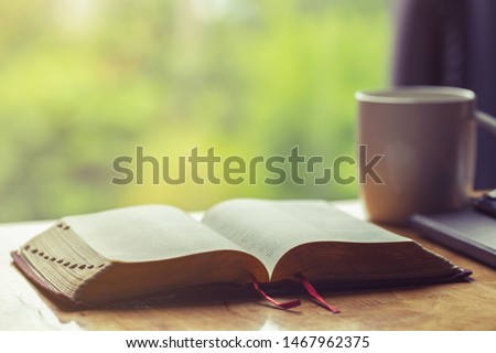  Open bible with a cup of coffee for morning devotion on wooden table with window light Royalty-Free Stock Photo #1467962375