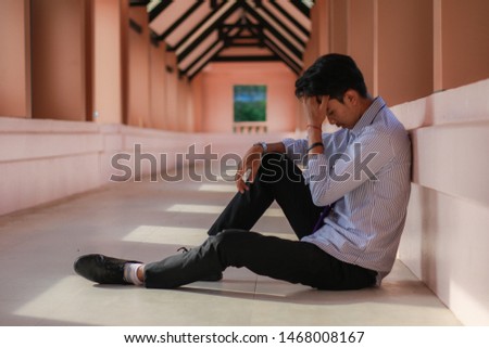 The hopeless man sits on the walkway, Desperate male company employee, Unemployment concept,Men who are stressed about finding work on the internet after being dismissed. Royalty-Free Stock Photo #1468008167
