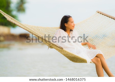 Portrait beautiful young asian woman sitting on hammock around sea beach ocean for relax in holiday vacation travel concept