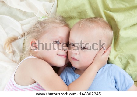 Happy kids - sister and brother relaxing on a bed