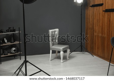 Stylish silver chair and professional equipment in photographer's studio
