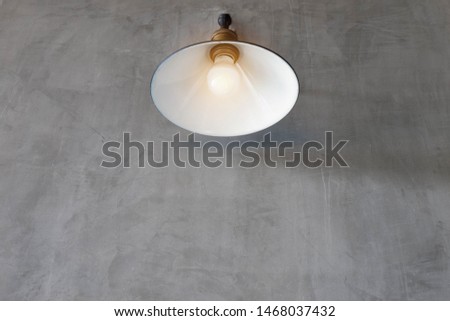 Classic vintage lamp with illuminating bulb on vintage loft style grey wall. Concept idea for background optimistic thinking media. 