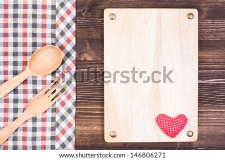 Color tablecloth textile, sign board with heart, spoon, fork on wooden background