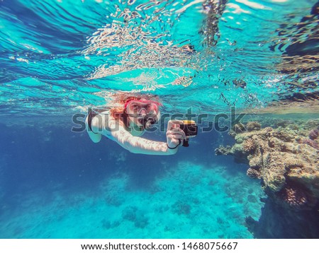 Snorkeling Girl with an action camera floats in the sea and shoots a video camera Royalty-Free Stock Photo #1468075667