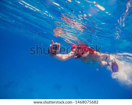 Snorkeling Girl with an action camera floats in the sea and shoots a video camera