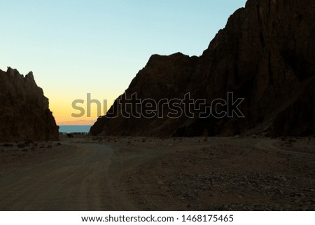 sand road in between mountains leading to the sea 