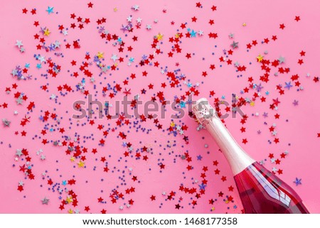 Party with champagne bottle and colorful party streamers on pink background top view pattern