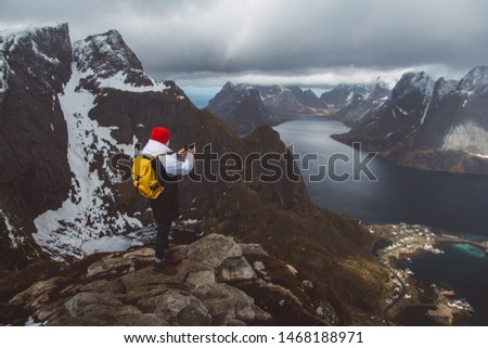 Man traveler taking photo with a smartphone hiking on Reinebringen mountain ridge in Norway lifestyle adventure traveling