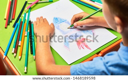 Child's hand drawing picture on paper