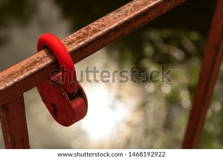 Close-up a red love lock hanging on a metal bridge railing	