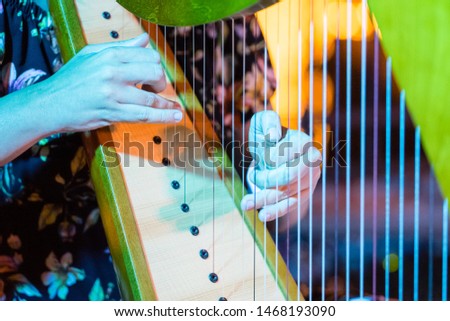 Close-up shot of female hands playing harp strings. Royalty-Free Stock Photo #1468193090
