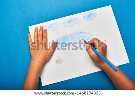 Little boy is drawing with pencil car