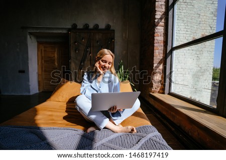 Smiling attractive woman lying on bed using laptop