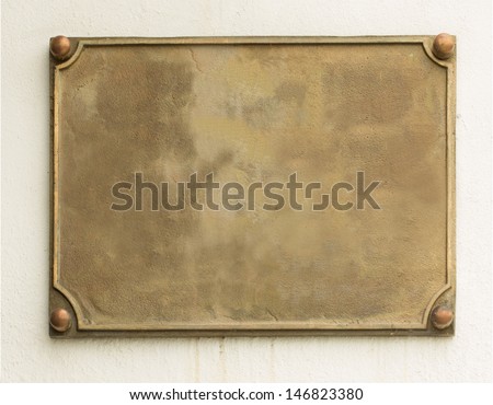 Old brass yellow metal plate framed and nailed on white stone wall background