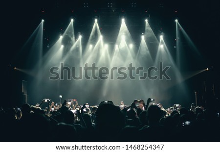 Concert crowd and stage background. Bright lights illuminating music festival scene.