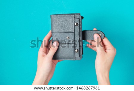 Women's hands open leather wallet on blue background. Top view