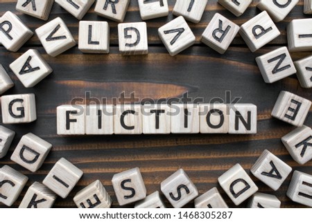 fiction - word from wooden blocks with letters, Literary Genres concept, random letters around, top view on wooden background
