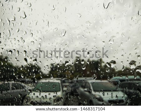 Rain drops on a glass with a blurred car park background