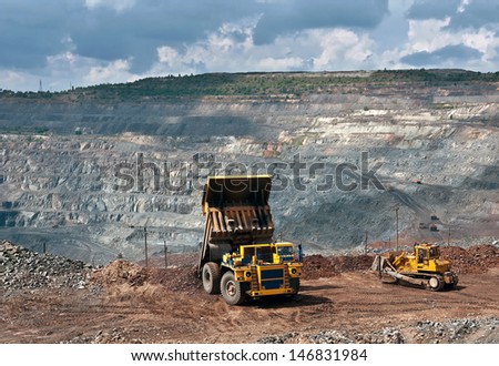 A picture of a big yellow mining truck and bulldozer at work site