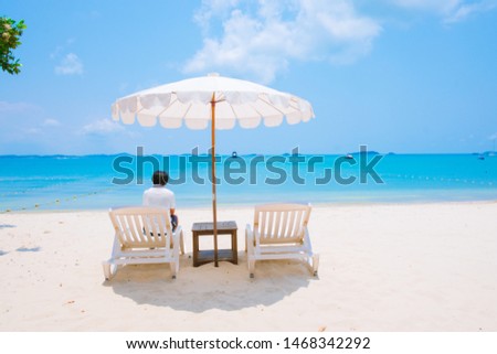 A man of sea view on beautiful tropical beaches vacation holiday relax in the sun on their deck chairs under a umbrella.