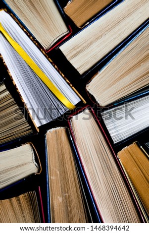 Lots of colourful thick open books stand on a dark background