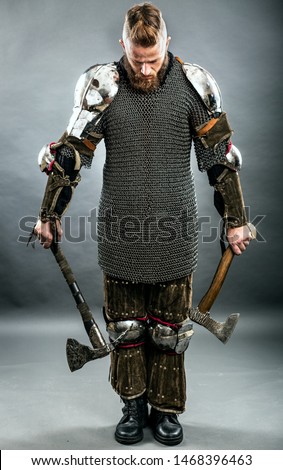 Medieval warrior berserk Viking with axes attacks the enemy. Concept historical photo