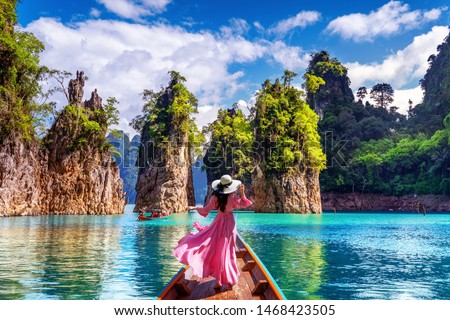 Beautiful girl standing on the boat and looking to mountains in Ratchaprapha Dam at Khao Sok National Park, Surat Thani Province, Thailand. Royalty-Free Stock Photo #1468423505