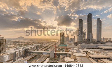 Sunrise aerial view of shopping mall and traffic morning timelapse with under construction building with cranes from downtown, colorful sky. Dubai Creek harbor on background
