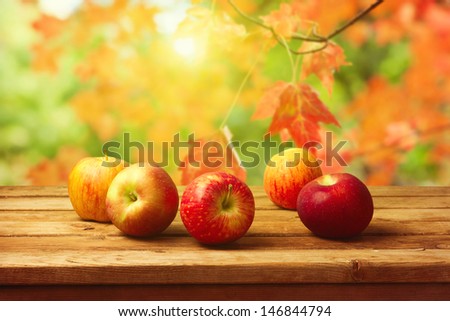 Apples on wooden table over autumn bokeh background