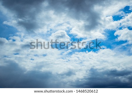 Cloudy sky with white and gray clouds on a background of blue sky.
